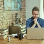 Older man tele working with laptop computer at home office