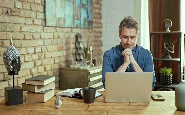 Older man tele working with laptop computer at home office